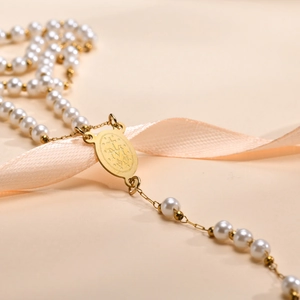 Detailaufnahme der Jungfrau-Maria-Medaille und Kunstperlen auf der religiösen Goldkette