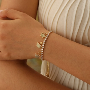Close-up of golden crown charm bracelet with pavé cubic zirconia on model wrist