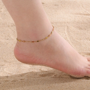 Bracelet de cheville doré en acier inoxydable avec charmes ronds colorés sur la plage
