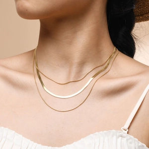 Gros plan sur un collier triple rangée en acier inoxydable plaqué or 18 carats avec chaîne serpent