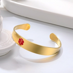 Detail of gold stainless steel medical alert cuff bracelet with red Star of Life symbol