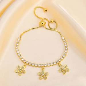 Detail of adjustable gold tennis bracelet with zircon-encrusted flower charms on satin