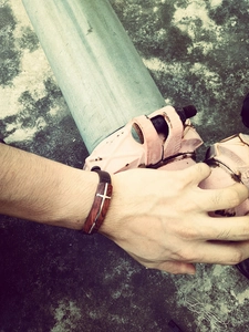 Macro shot of men's leather bracelet featuring rosewood inlay and metal cross detail