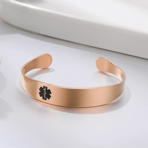 Detail of rose gold medical alert cuff bracelet with brushed metal and Star of Life
