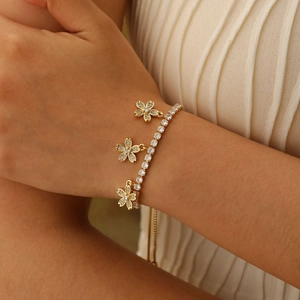 Close-up of gold tennis bracelet featuring sparkling zircon flowers on a woman's wrist