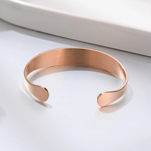 Macro detail of rose gold open cuff bracelet with polished finish and brushed inner metal