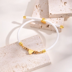 Detail of adjustable white braided rope bracelet with polished gold heart and slide buckle