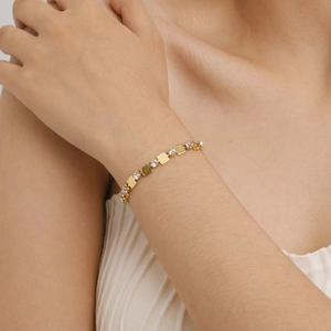 Détail d'un bracelet en or 18 carats avec maillons carrés et zircons porté au poignet