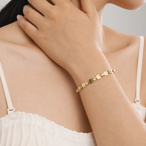 Gros plan d'un bracelet en plaqué or 18 carats avec zircons porté au poignet d'une femme