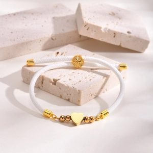 Adjustable white woven rope bracelet featuring a gold heart charm and metallic beads