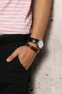 Detail view of a men's brown leather bracelet with stripes paired with a silver watch