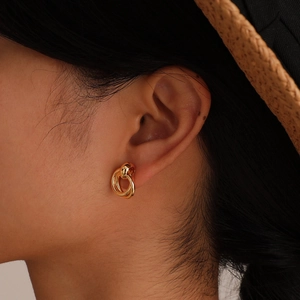 Close-up of golden multi-layer intertwined hoop earrings on female model