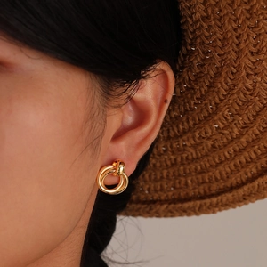 Chic gold-tone double hoop twisted earrings worn by a model with a summer straw hat