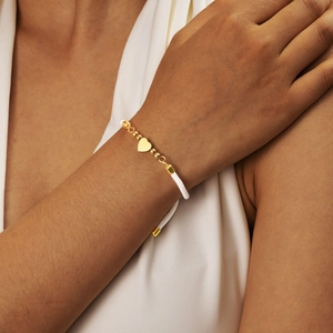 Detailed shot of gold heart charm and beads on white adjustable rope bracelet for women