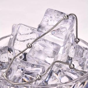 Macro shot of silver beaded snake chain anklet displayed on ice cubes for elegant texture