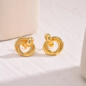 Detailed view of intertwined gold twist earrings on minimalist display stand