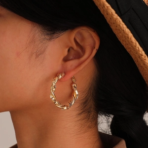 Golden spiral textured large hoop earrings shown on a model with elegant metallic finish