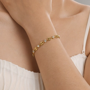 Détail d'un bracelet maille grain de café doré 18 carats avec zircons sur le poignet
