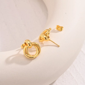 Macro shot of gold twist double-hoop earrings with high-polish finish on ceramic prop