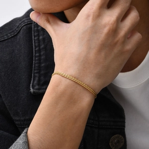 Détail d'un bracelet pour homme en acier inoxydable doré tressé porté au poignet