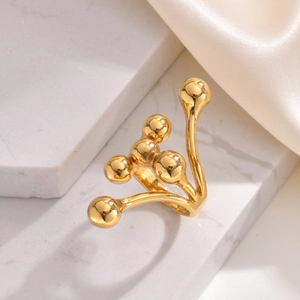 Bague ouverte en acier doré avec billes métalliques sur marbre blanc pour femme