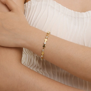 Détail d'un bracelet en or 18 carats avec croix et zircons porté sur le poignet