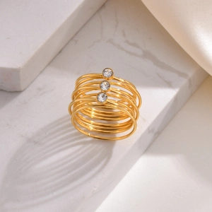 Bague multicouche en acier inoxydable doré avec trois zircons ronds sur marbre