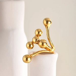 Macro d'une bague à perles dorées en acier inoxydable sur un vase blanc texturé