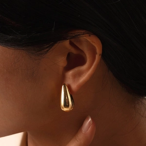 Polished gold waterdrop stud earrings for women with a sleek mirror finish on a model