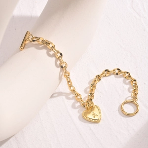Close-up of gold heart pendant with letter A and toggle clasp on stainless steel bracelet
