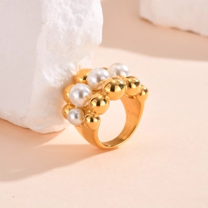 Detail of layered gold stainless steel ring with white pearls and beads on stone
