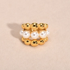 Detail of multi-layered gold beads and white pearls in a luxurious triple-row ring
