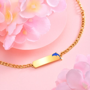 Close-up of golden NK chain bracelet featuring blue dolphin plate on pink floral background