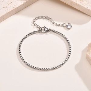 Détail d'un bracelet gourmette en acier inoxydable avec fermoir mousqueton et breloque zircon