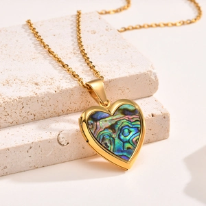 Macro detail of gold heart locket necklace with iridescent abalone shell inlay on stone