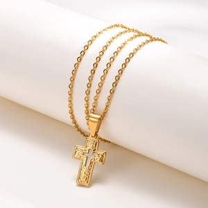 Detail shot of golden stainless steel cross pendant with intricate floral relief carving