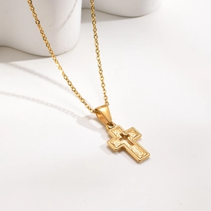 Close-up of golden stainless steel cross pendant with detailed vintage embossed patterns