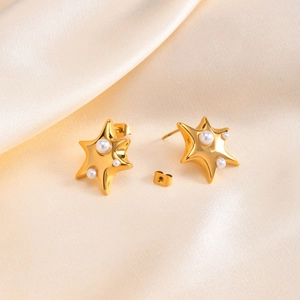 Boucles d'oreilles étoiles dorées élégantes avec perles blanches sur soie champagne