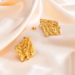 Gold stainless steel stud earrings with irregular lava texture on champagne silk fabric
