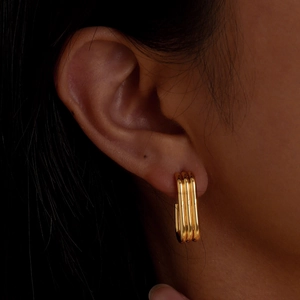 Boucles d'oreilles créoles dorées en acier inoxydable à trois couches sur un mannequin