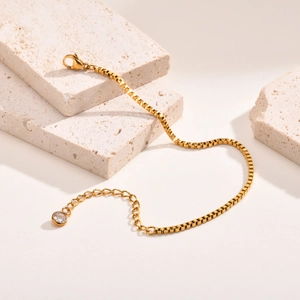 Détail d'un bracelet maille vénitienne dorée avec fermoir mousqueton et pendentif zircon