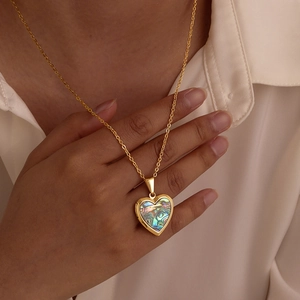 Detailed close-up of a heart-shaped gold necklace pendant featuring colorful abalone shell