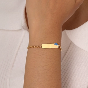Golden Figaro chain bracelet with a blue dolphin pendant and metal plate on wrist