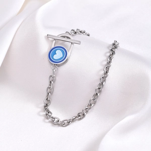 Vue détaillée du bracelet en acier argenté avec breloque cœur bleu sur fond de soie