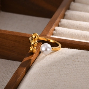 Detailed view of gold stainless steel open ring with three beads and a white pearl