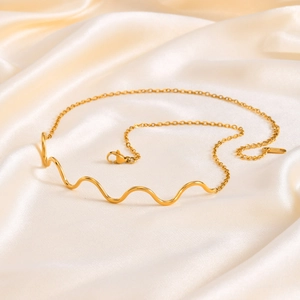 Polished gold wavy line necklace on silk fabric, elegant minimalist stainless steel jewelry