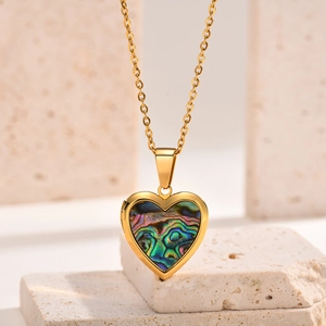 Golden heart locket necklace with colorful abalone shell inlay on travertine stone