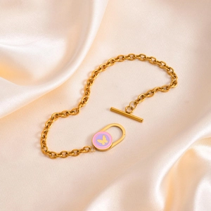 Détail d'un bracelet doré à gros maillons avec pendentif papillon rose et fermoir en T