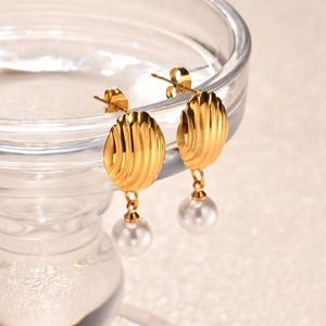 Macro view of gold stainless steel shell texture stud earrings with round white pearl drop
