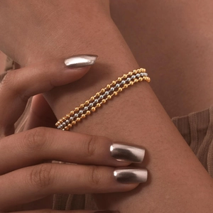 Close-up of three-layered gold and silver beaded bracelet on wrist for a minimalist style